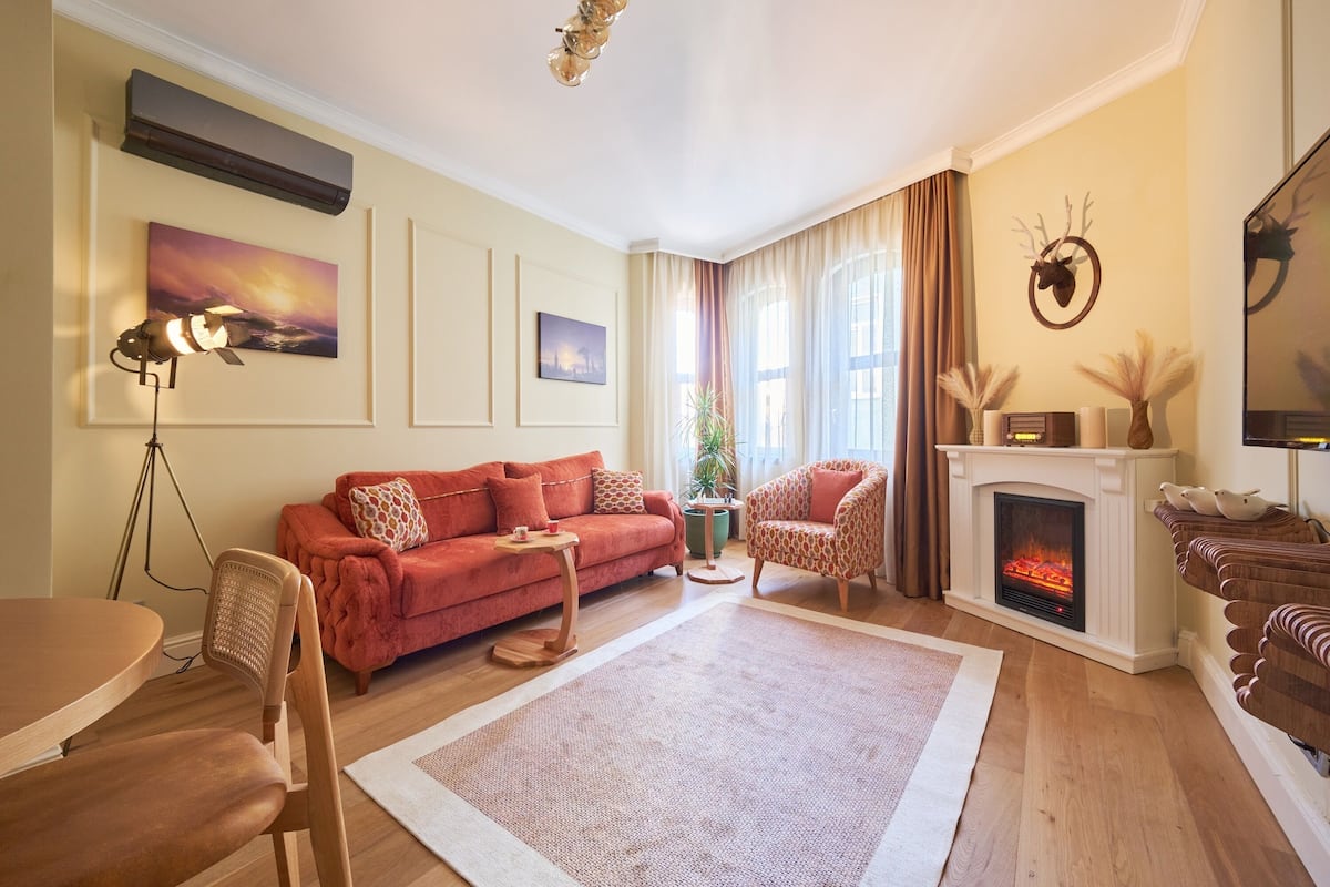 Una sala de estar con sofá, sillón, chimenea y un cuadro en la pared.