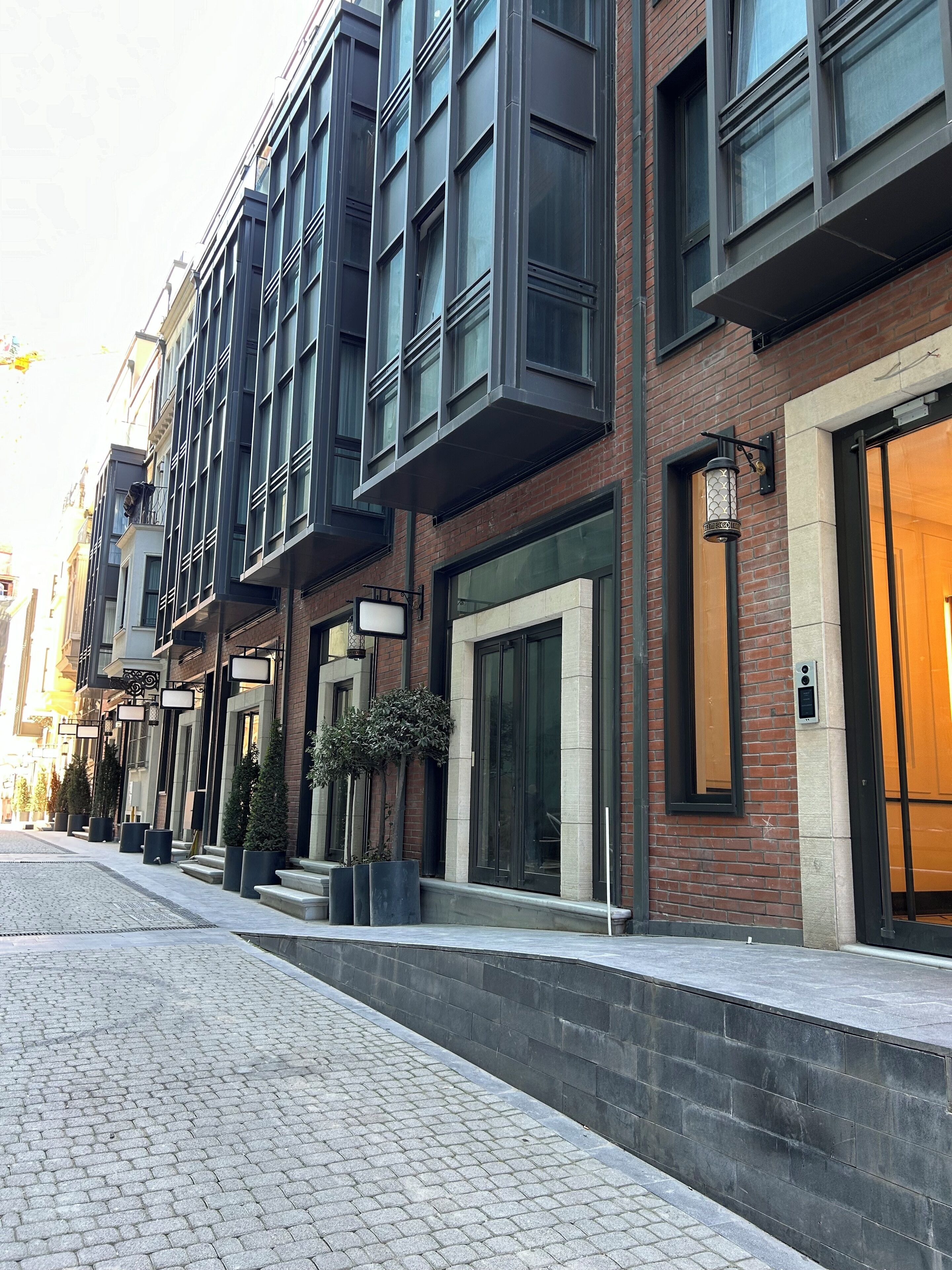 A modern building with a brick facade, large windows, and a well-maintained sidewalk.