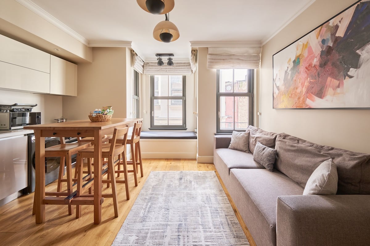 Una cocina moderna con muebles de madera, comedor y un ventanal grande.