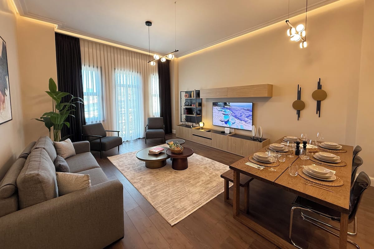Una sala moderna con sofá, mesa de centro y comedor listo para una comida.