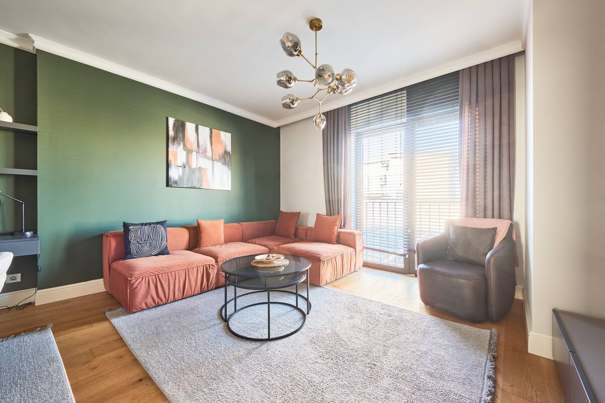 Una sala de estar moderna con un sofá modular, una mesa de centro redonda y un sillón de cuero.