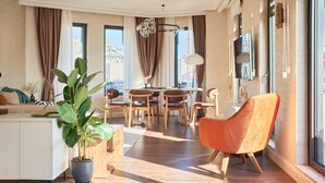 Een moderne woonkamer met een eetgedeelte, grote ramen en een potplant.