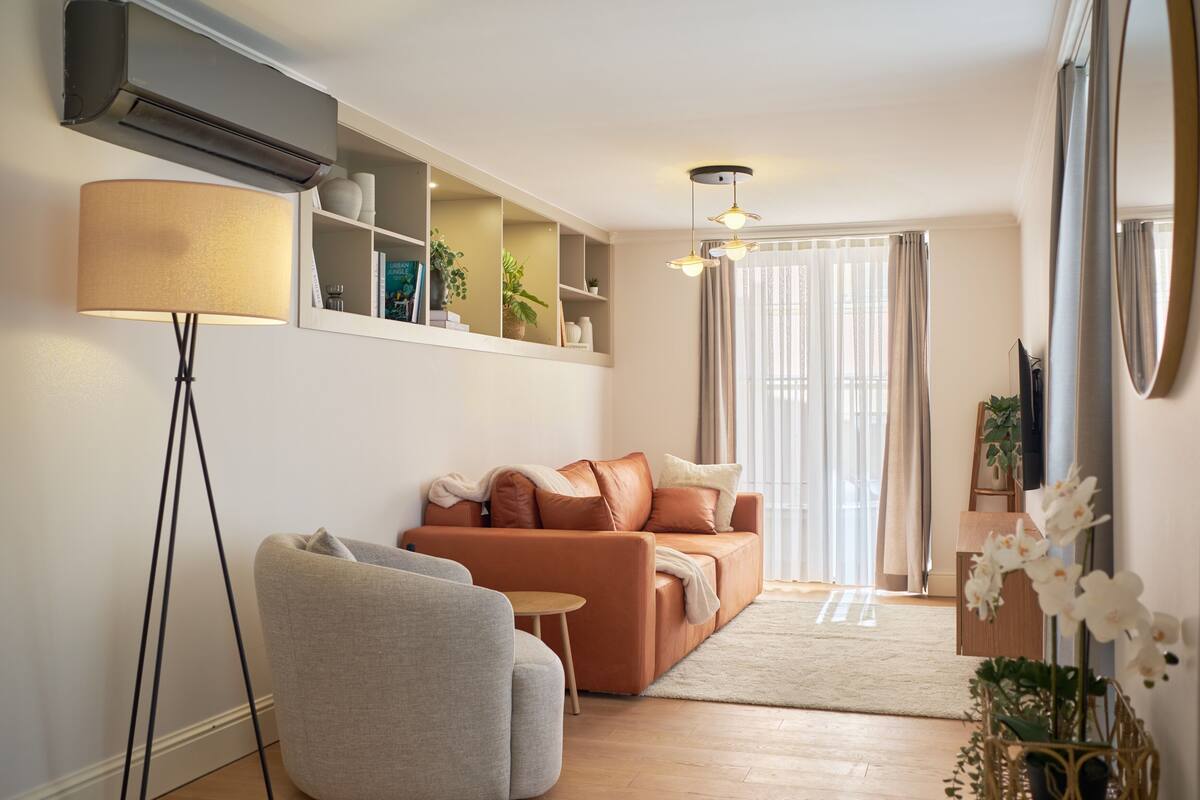 Una sala de estar moderna con un sofá, un sillón, una lámpara de pie y una mesita.