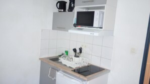 Une cuisine compacte équipée d’un four à micro-ondes, d’une machine à café et d’un évier avec un égouttoir à vaisselle.