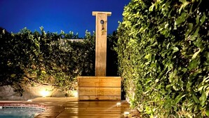 Una terraza de madera que conduce a una piscina con una estructura de madera en el centro.