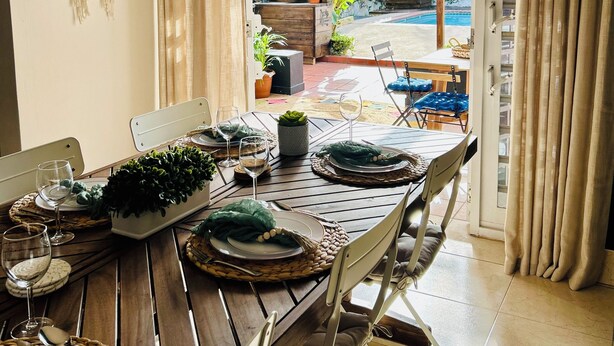 Un comedor con una mesa dispuesta para cuatro, incluyendo platos, vasos y cubiertos.
