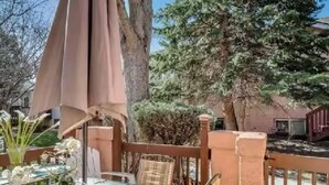 An outdoor patio with a glass table, chairs, and a large umbrella. - Great location for your Aurora visit (Aurora)