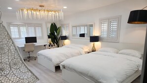 Ein modernes Schlafzimmer mit zwei Betten, einem Schreibtisch und einem Hängekorbstuhl.