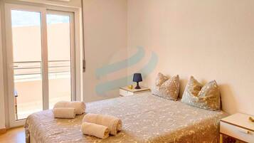 A bedroom with a bed, a nightstand, a lamp, and a view through a sliding door.