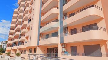 A multi-story building with balconies, air conditioning units, and a pedestrian walkway.
