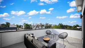 Une terrasse sur le toit avec un canapé, des chaises et une table.