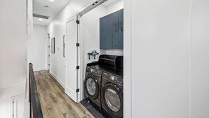 Une buanderie moderne équipée de deux machines à laver à chargement frontal et d’un grand miroir placé au-dessus.