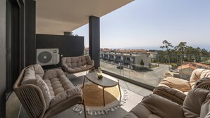 En balkon med sofaarrangement, et rundt bord og udsigt over bybilledet.
