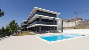 En moderne bygning med to etager, en swimmingpool og udendørs siddepladser.