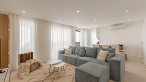 En moderne stue med en grå modulsofa, et lille hvidt bord og en beige måtte.