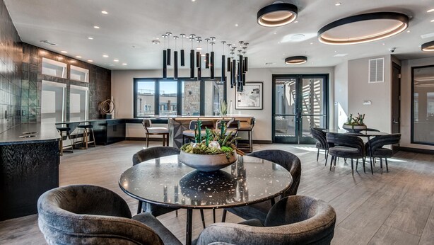 Une cuisine moderne dotée d’un îlot central, d’un bar et d’un coin repas avec des tables et des chaises rondes.