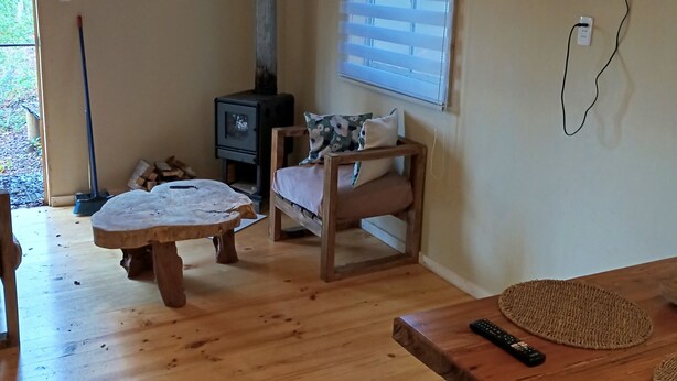 A cozy room with a wooden dining table, a sofa, and a TV mounted on the wall. - El roble cabins (Caburgua)