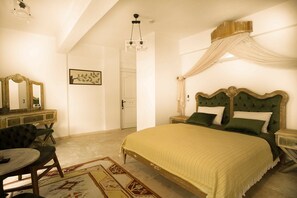 A bedroom with a large bed, a vanity with a mirror, and a chair. - B&Y Burgaz (Selcuk)