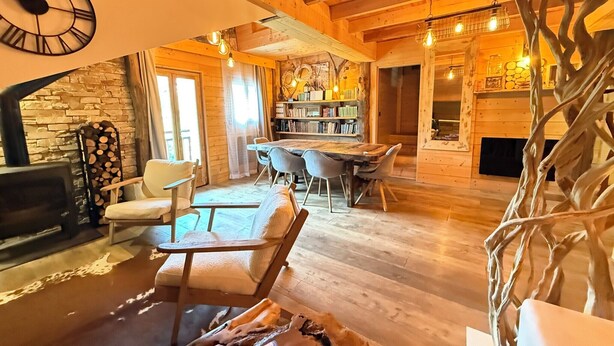 A cozy wooden interior with a fireplace, a dining area, and a bookshelf.