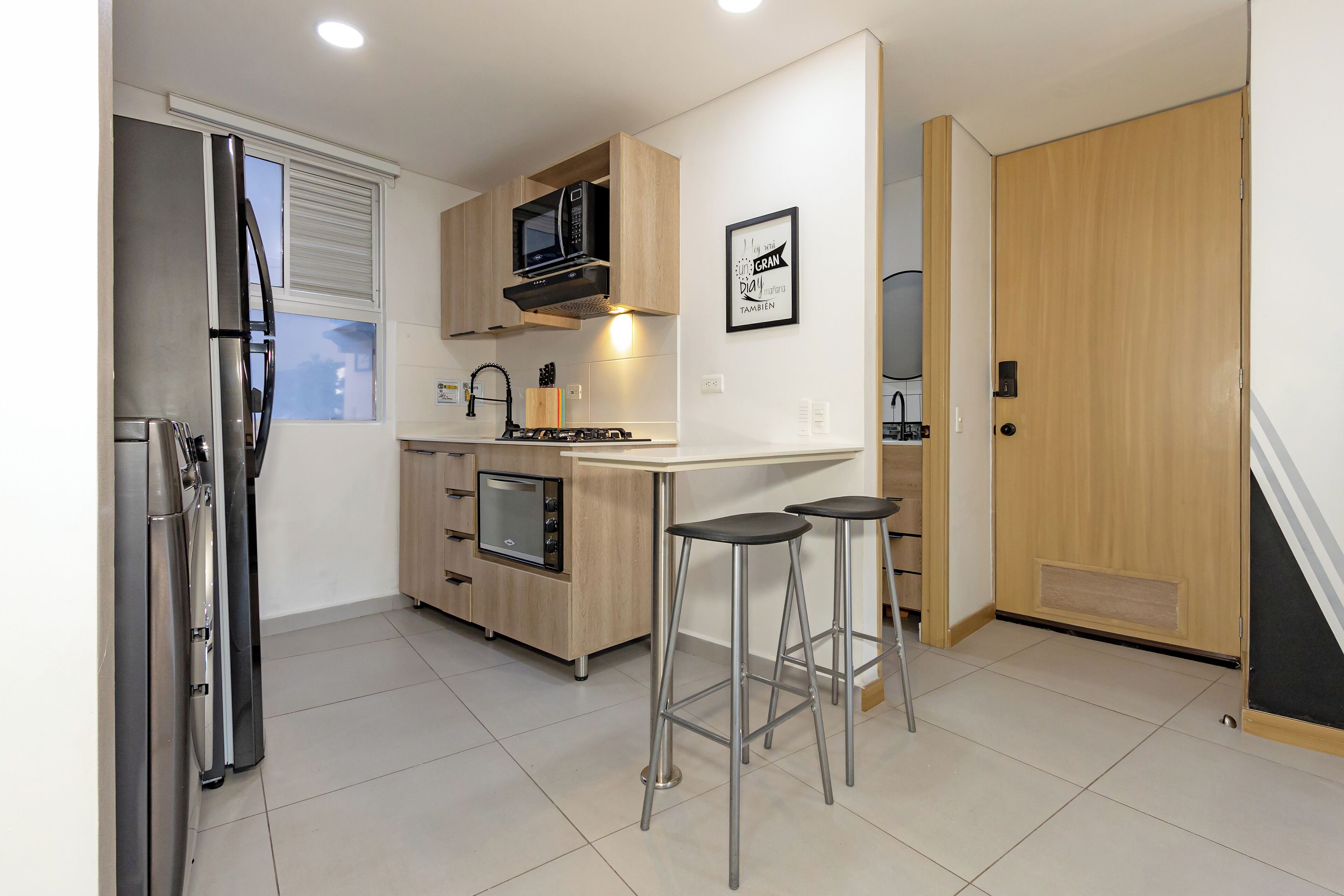 A modern kitchen with stainless steel appliances, wooden cabinets, and a bar stool area.