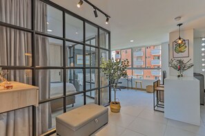 Ein modernes Hotelzimmer mit großem Fenster, Schreibtisch, Bank und Pflanze.