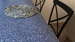 A dining table with a blue speckled surface and two woven placemats. - 3 Bedroom - Creek Access Alaskan Blackstone Retreat (Anchorage)