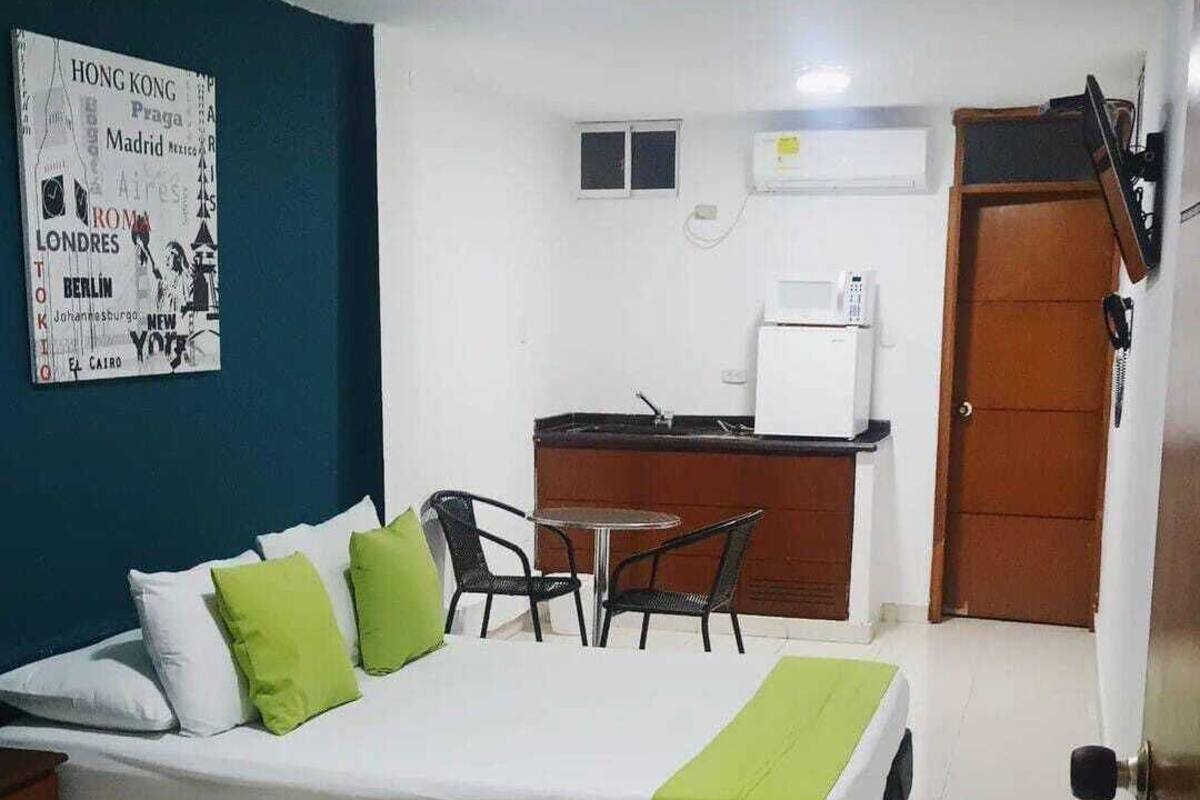 Ein Hotelzimmer mit Bett, Schreibtisch und Stuhl. An der Wand hängt ein Poster und rechts ist eine Tür.