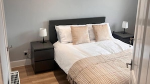 A bedroom with a bed, two bedside tables, and a wall-mounted painting.