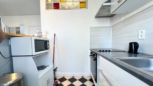 Une cuisine compacte équipée d’un four à micro-ondes, d’une cuisinière et d’un évier.
