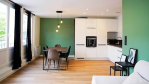 Una cocina moderna con armarios blancos, una mesa de comedor con sillas y un colgador de luces.