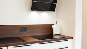 Una cocina moderna con encimera de madera oscura, armarios blancos y una campana extractora negra.
