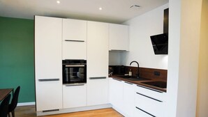 Una cocina moderna con armarios blancos, horno empotrado, campana extractora negra y encimera de madera.