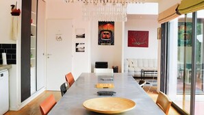 Un comedor moderno con una mesa larga, sillas de madera y una araña.