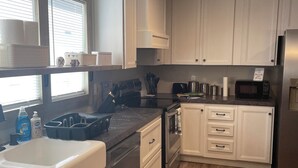 Una cocina con gabinetes blancos, un refrigerador de acero inoxidable, un microondas y un lavamanos.