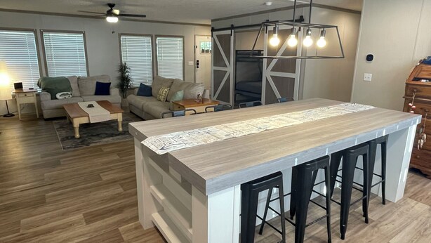Una cocina moderna con una isla central, taburetes de bar y una zona de comedor con sofá y mesa de centro.