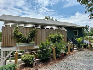 Ein Haus mit einer Holzterrasse, einer überdachten Veranda und einer Schotterauffahrt.