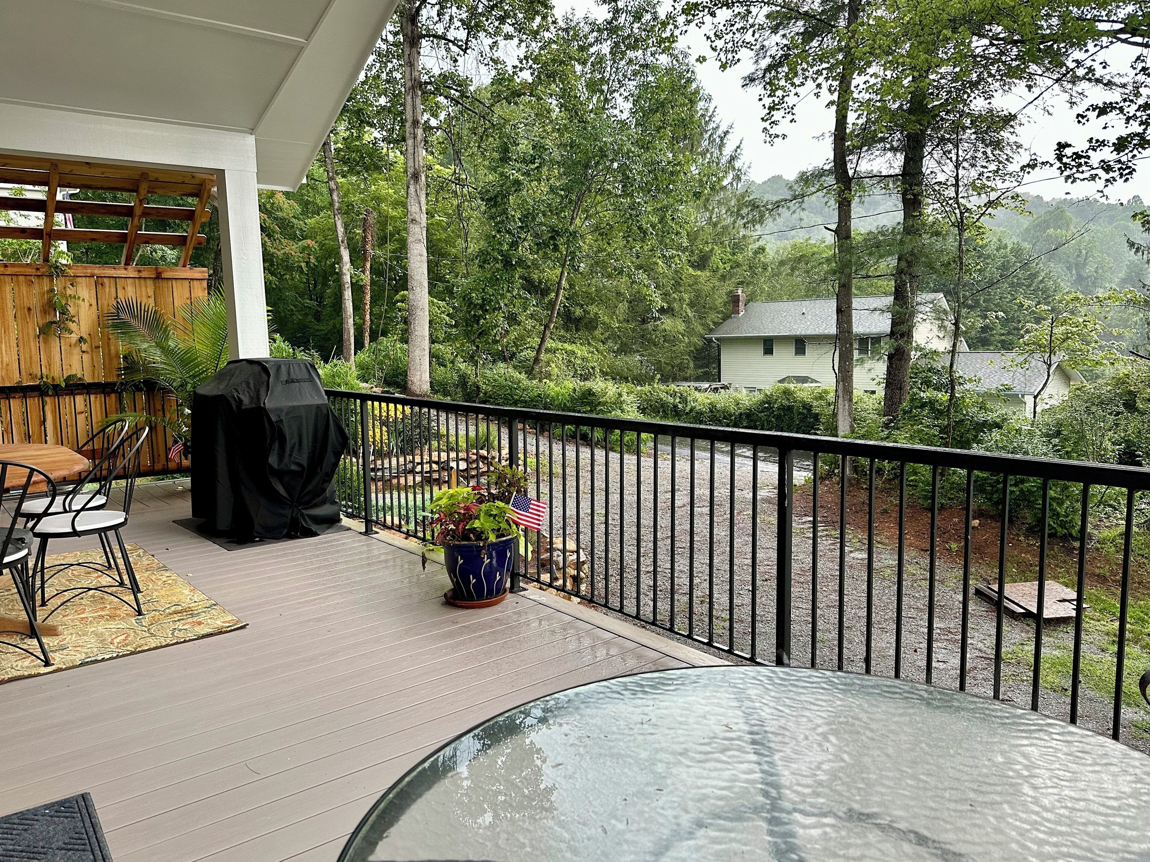 Une terrasse couverte avec une table et des chaises, un barbecue et un pot de fleurs orné d’un drapeau américain.