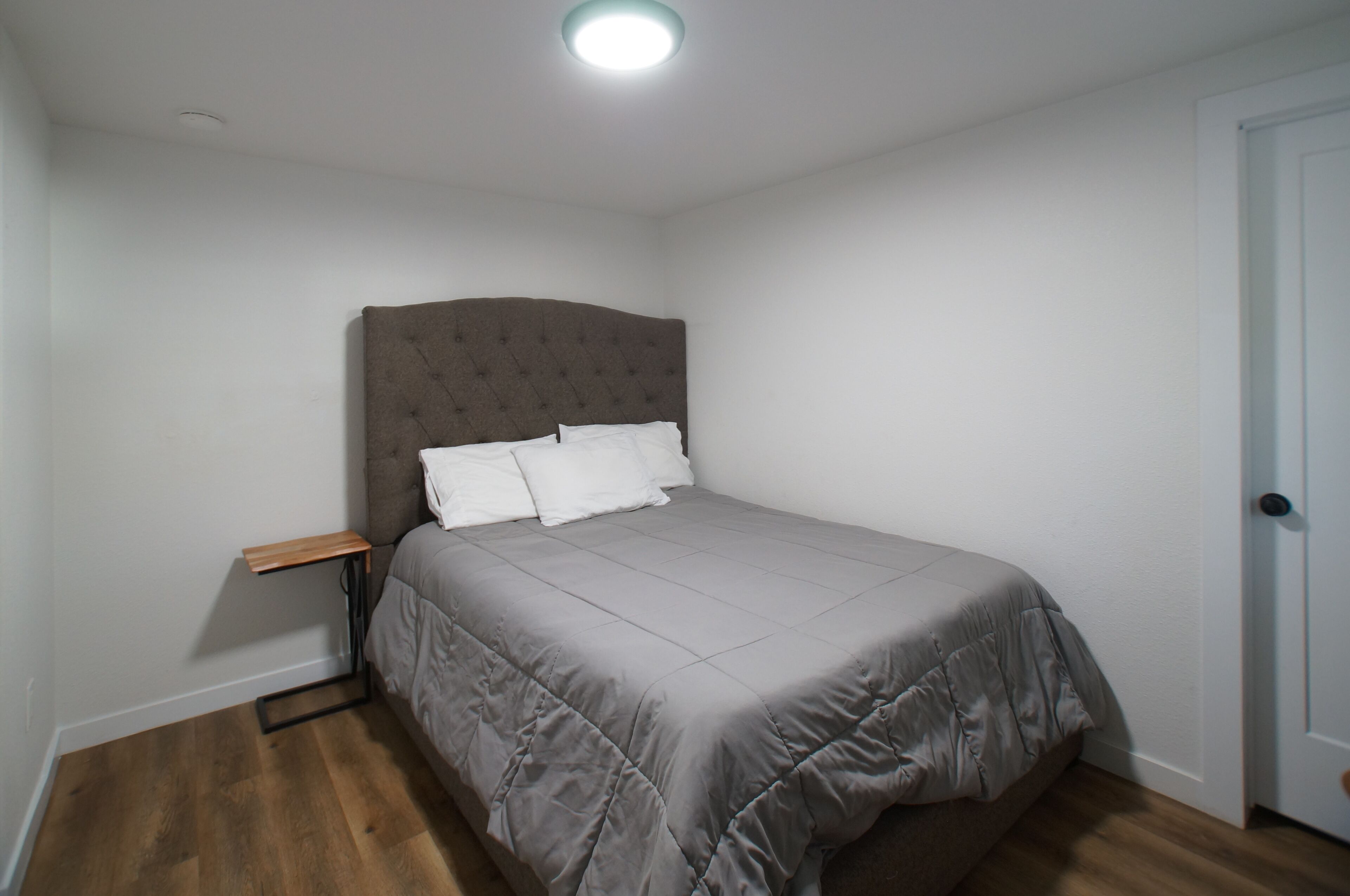 Un dormitorio con una cama, una mesita de noche y una puerta.