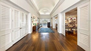 Un couloir doté d’un plancher en bois, de portes blanches et d’un lustre.