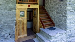 A rustic wooden building with a stone exterior, a wooden staircase, and a balcony.