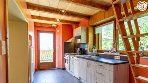 A modern kitchen with wooden cabinets, a large window, and a view of greenery.