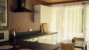Een keuken met een bakstenen muur, een fornuis, een magnetron en een eethoek met stoelen en een tafel.