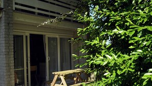 Een houten picknicktafel voor een gebouw met een glazen schuifdeur.