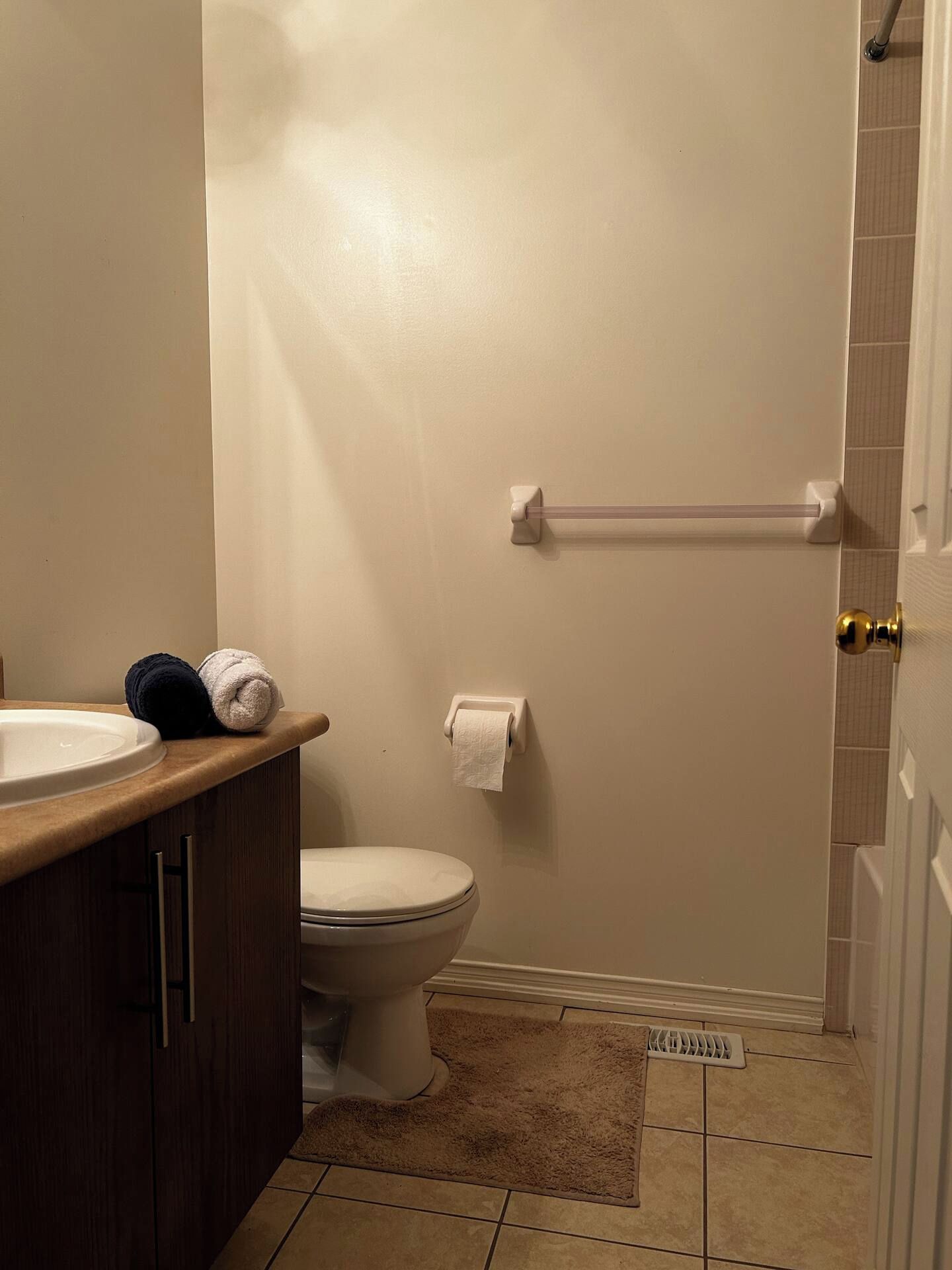 A bathroom with a toilet, a sink, a towel rack, and a shower area.