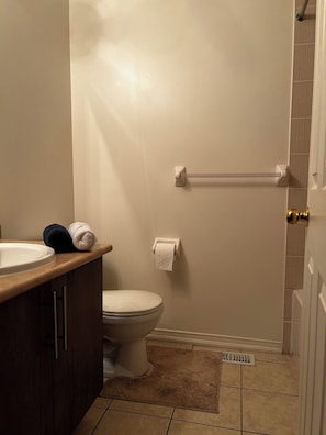 A bathroom with a toilet, a sink, a towel rack, and a shower area. - Private Room in Ajax (Ajax)