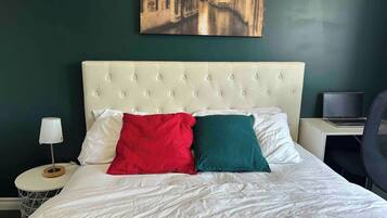 Une chambre d’hôtel avec un lit, un ordinateur portable posé sur un bureau et un tableau accroché au mur.