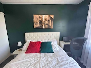 A hotel room with a bed, a desk, a chair, a lamp, and a painting on the wall. - Private Room in Ajax (Ajax)