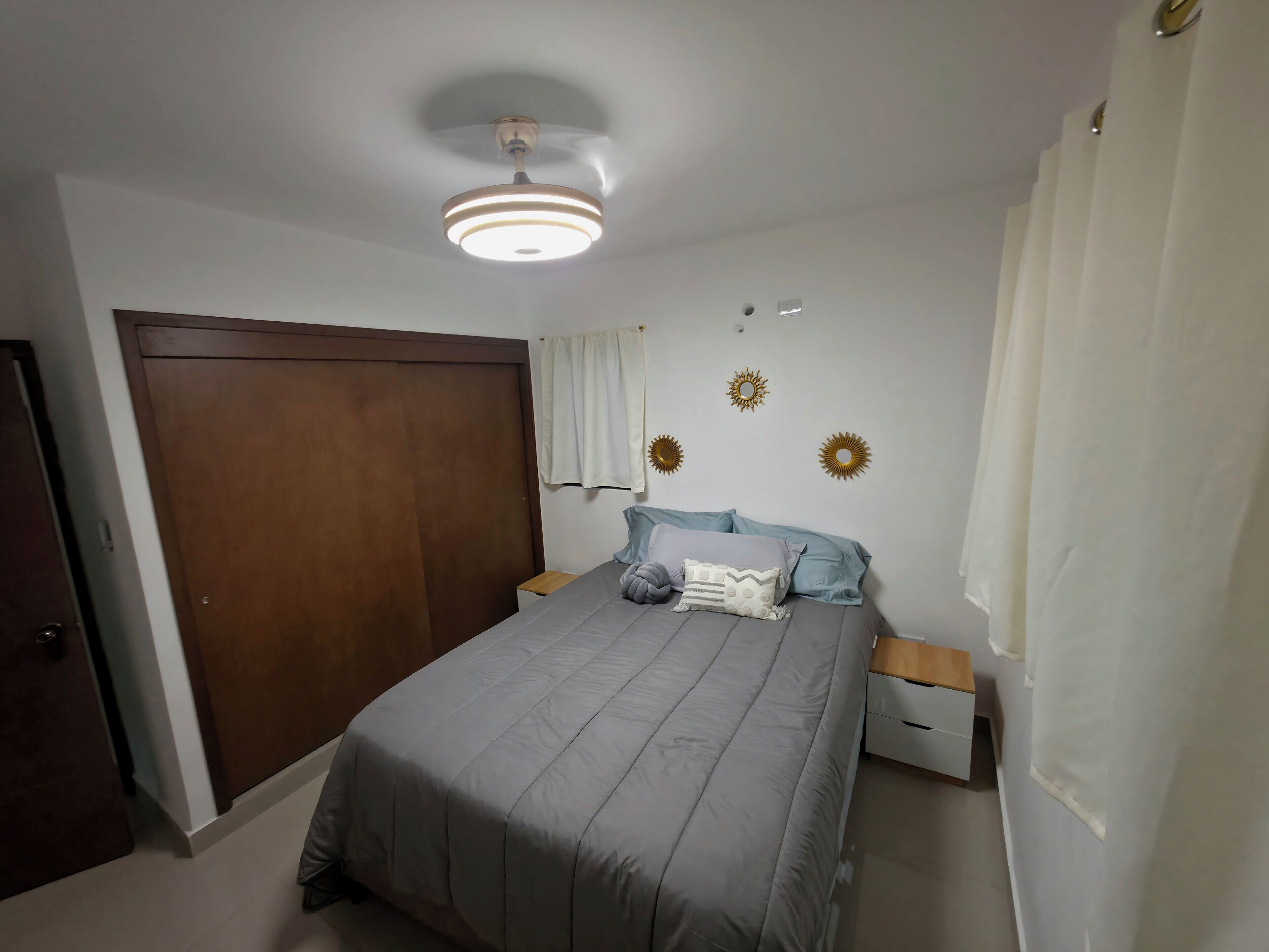 A bedroom with a bed, nightstands, a wardrobe, and decorative wall elements.