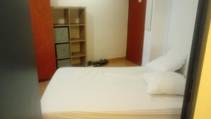 A bedroom with a bed, a wooden wardrobe, and a shoe rack. - The Popes' Refuge (Avignon)
