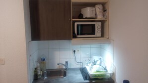 A small kitchen with a microwave, a sink, and a dish rack. - The Popes' Refuge (Avignon)